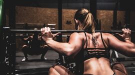 Kvinna gör knäböj med skivstång i ett gym